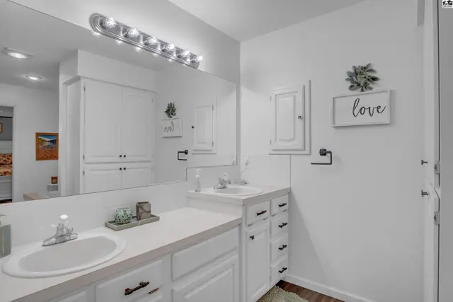 Bright white bathroom with double vanity, ample storage, and modern fixtures.