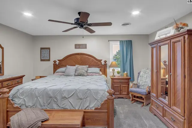 Spacious bedroom with a large wooden bed frame, matching furniture, and blue accents.