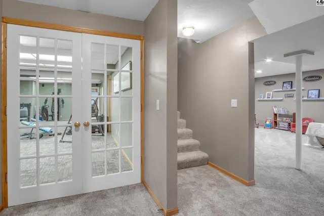 French doors open to a home gym, with carpeted stairs leading to a finished basement.