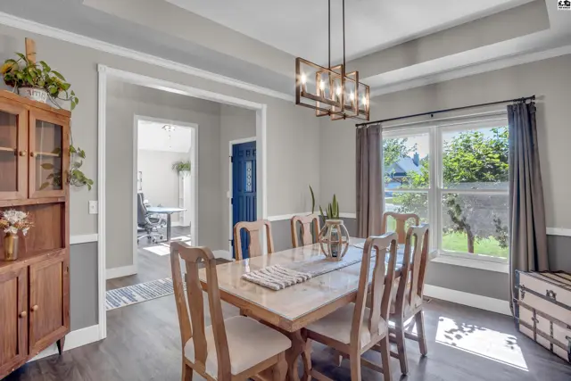 Elegant dining room with a wood table, chairs, coffered ceiling, and a view of the backyard.