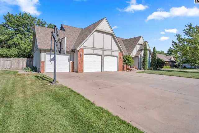 Spacious home exterior with a three-car garage, brick accents, and a basketball hoop.