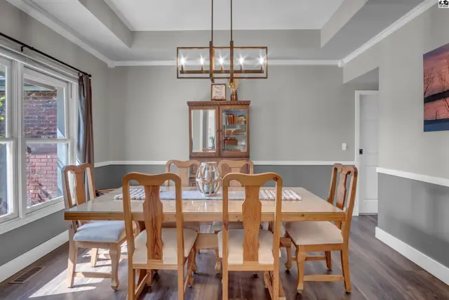 Elegant dining room with a coffered ceiling, wood furniture, and two-tone gray walls.