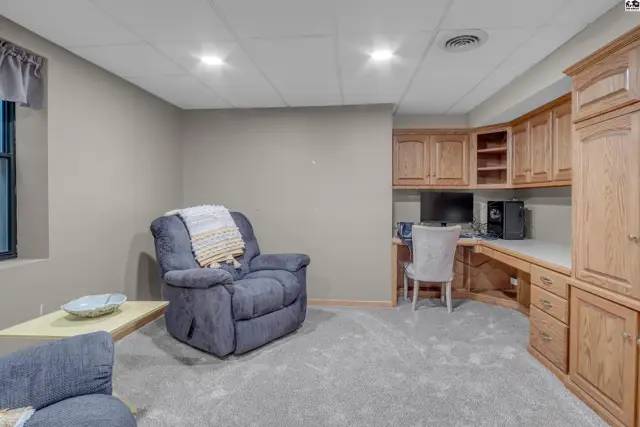 Cozy living area with plush blue recliner, built-in oak desk, and neutral carpet.