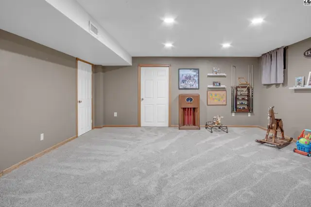 Spacious finished basement with plush gray carpet, neutral walls, and recessed lighting.