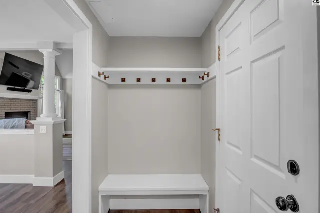 Entryway with white bench, coat rack, and white paneled door.