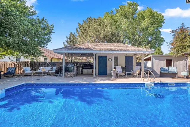 Spacious backyard with a large blue swimming pool and covered outdoor kitchen area.