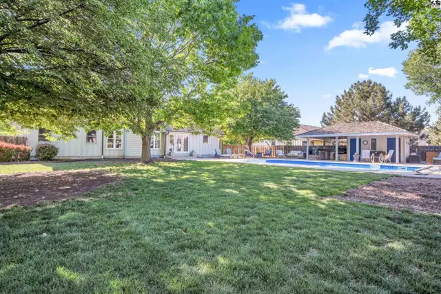 Spacious backyard features a large swimming pool and covered patio area, surrounded by mature trees.