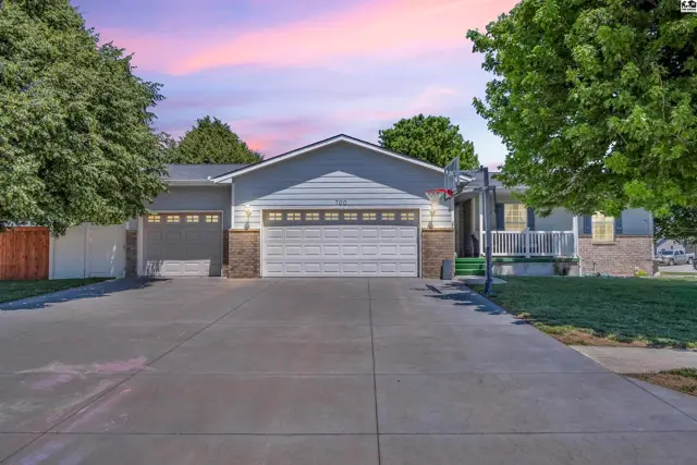 Spacious ranch home with a light blue exterior, brick accents, and a large driveway.