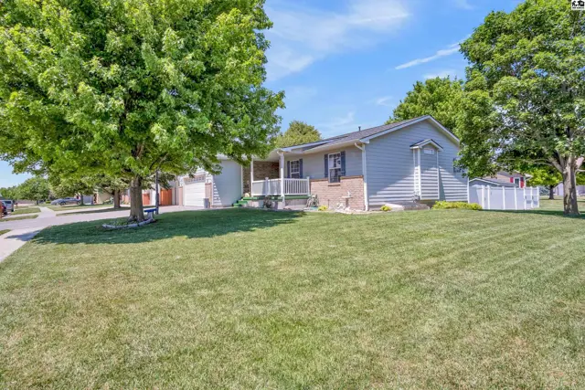 Light blue siding and brick exterior of a ranch home with a manicured lawn and mature trees.