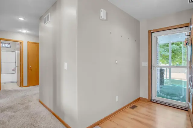 Entryway with light wood floors, neutral walls, and a glass door leading outside.