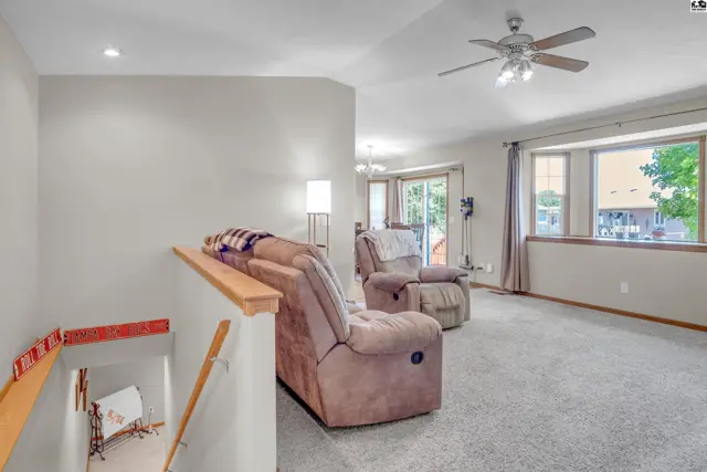 Spacious living room with plush recliners, neutral carpet, and large bay windows.