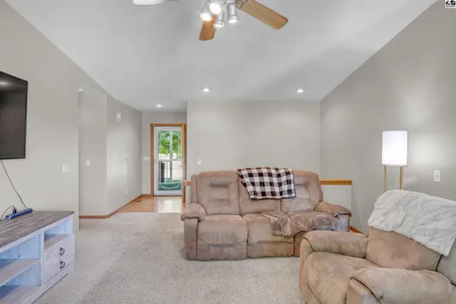 Spacious living room with plush carpet, neutral walls, and a cozy recliner.