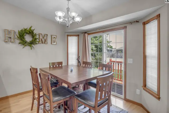 Dining area with a wooden table and chairs, bay window, and sliding glass door to a deck.