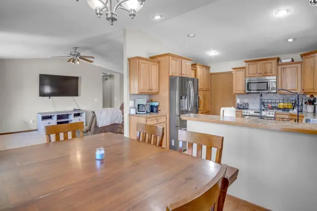 Spacious kitchen and dining area with light wood cabinets, stainless steel appliances, and a large wooden table.