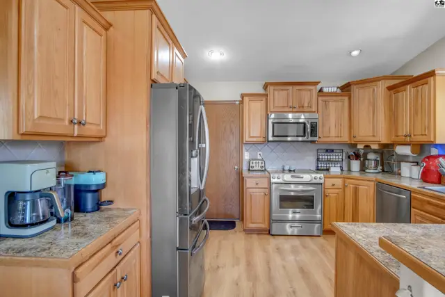 Spacious kitchen with light wood cabinets, stainless steel appliances, and granite countertops.