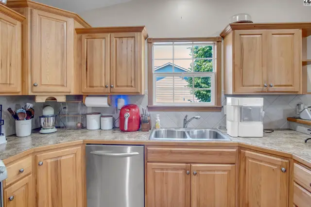 Kitchen with light wood cabinets, granite countertops, stainless steel appliances, and a double sink.