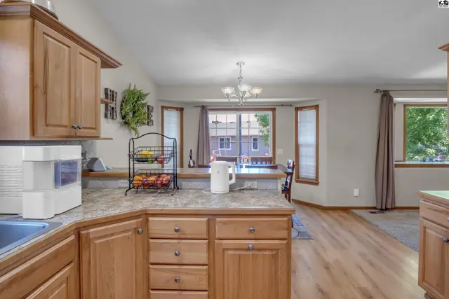 Spacious kitchen with light wood cabinets, granite countertops, and a breakfast bar overlooking a dining area.