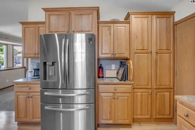 Spacious kitchen features stainless steel appliances and light wood cabinetry with ample storage.