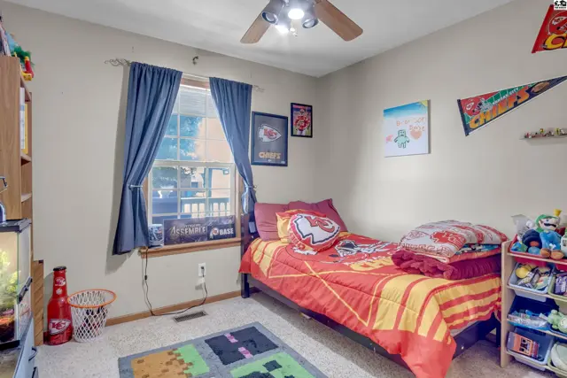 Cozy bedroom with a twin bed, Kansas City Chiefs bedding, and a ceiling fan.