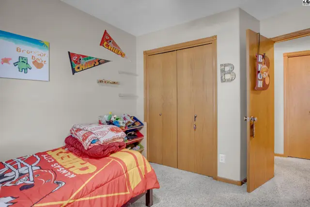 Bedroom with a twin bed, Kansas City Chiefs bedding, and a double closet with wood doors.