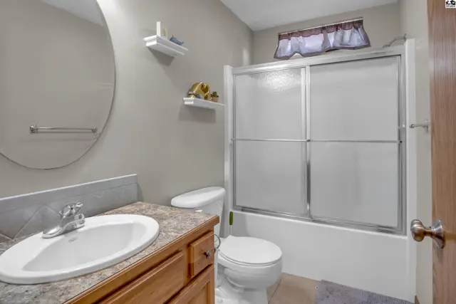 Modern bathroom with a vanity, toilet, and a sliding glass shower/tub enclosure.