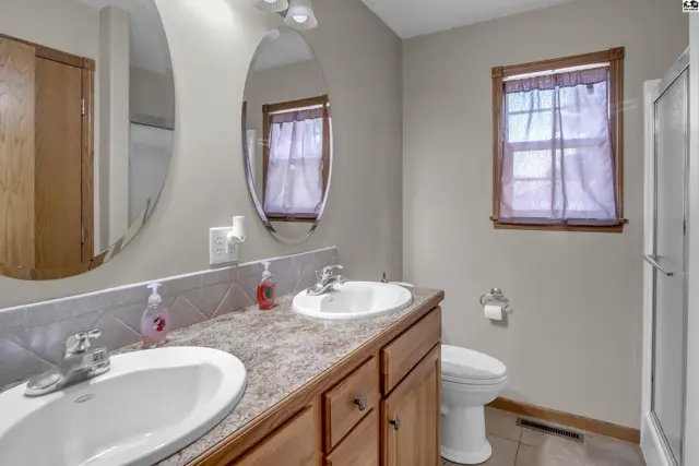 Spacious bathroom with double vanity, granite-look countertop, and wooden cabinetry.