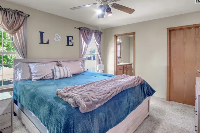 Spacious bedroom with a king-size bed, plush carpet, and a view of a bathroom vanity.