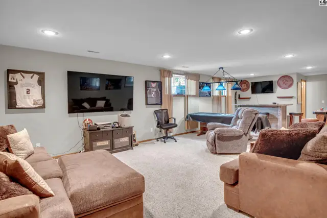 Spacious finished basement with pool table, bar, multiple TVs, and comfortable seating.