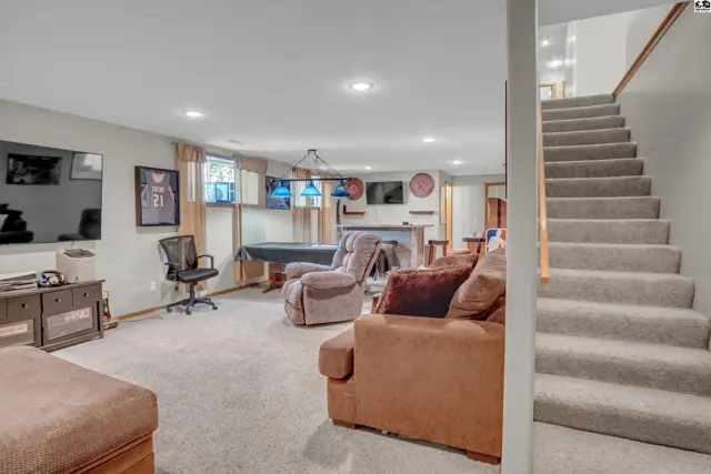 Spacious finished basement features a pool table, bar, and comfortable seating with plush carpet.
