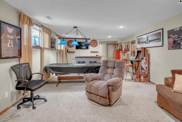 Spacious finished basement features a pool table, arcade game, and comfortable seating.