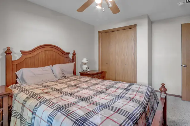 Bedroom with a wooden bed frame, plaid bedding, and a large closet.