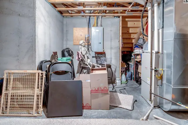 Unfinished basement with concrete walls, exposed joists, and HVAC equipment.