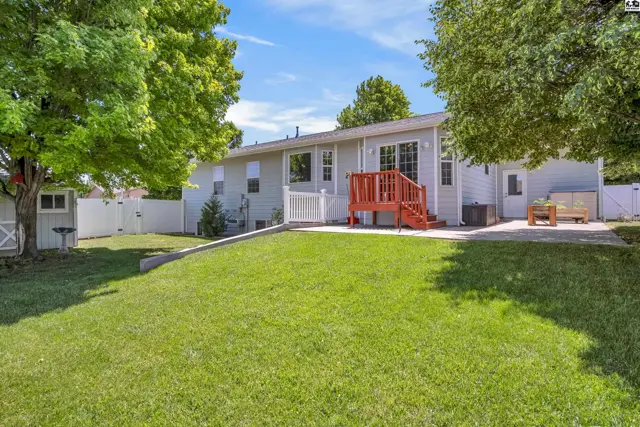 Spacious backyard with a bright red deck, white vinyl fence, and mature trees.