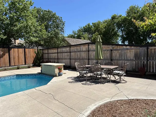 Backyard oasis with a sparkling pool, patio dining set, and a built-in stone bar.