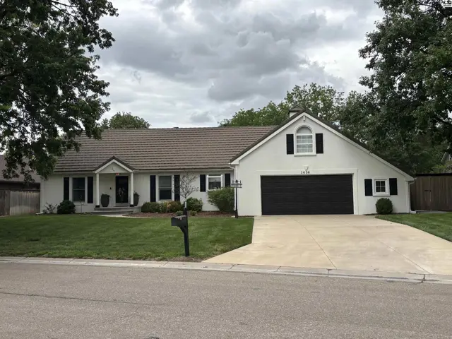 Charming white stucco ranch home with a tile roof, dark garage door, and manicured lawn.