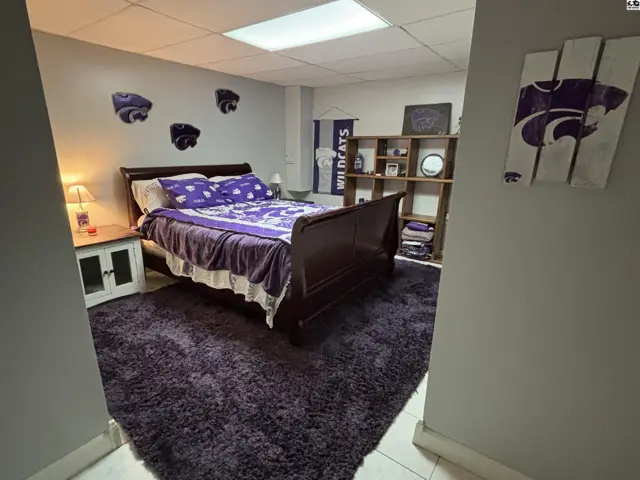 Bedroom with a dark wood sleigh bed, purple bedding, and Wildcats decor.