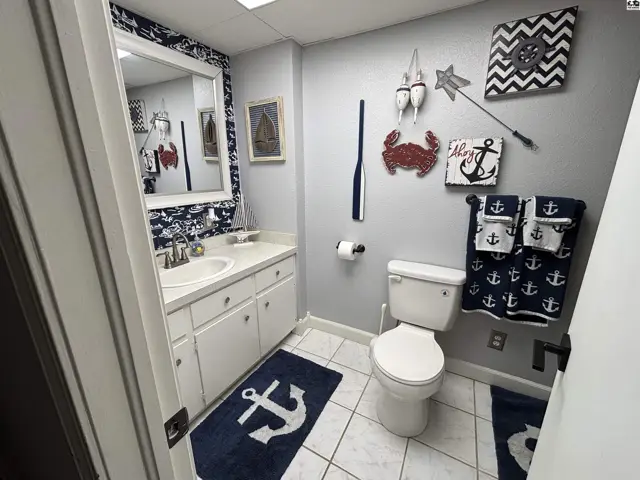 Nautical-themed bathroom with white vanity, tiled floor, and anchor-patterned decor.