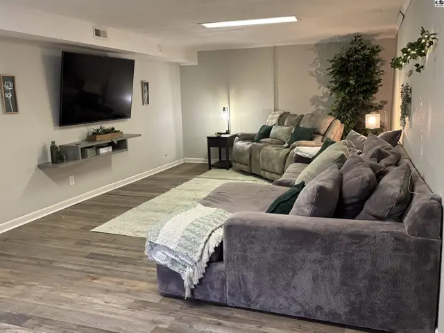 Spacious living room with plush sectional sofa, mounted TV, and wood-look flooring.