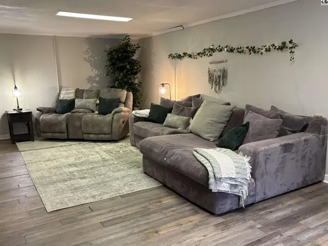 Spacious living room with plush sectional sofa, reclining loveseat, and light wood-look flooring.