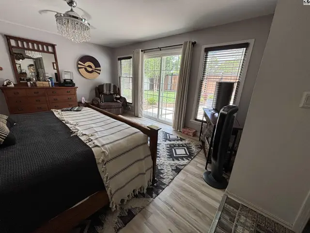 Spacious bedroom with a king-size bed, sliding glass doors to the backyard, and light wood-look flooring.