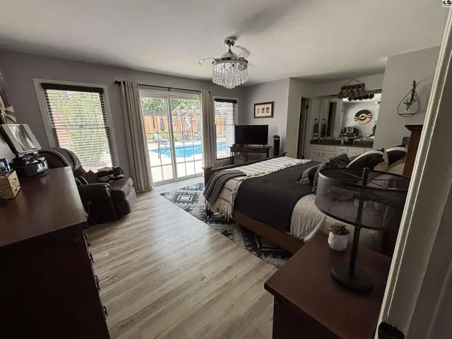 Spacious primary bedroom with a king-size bed, sliding glass doors to a pool, and wood-look flooring.