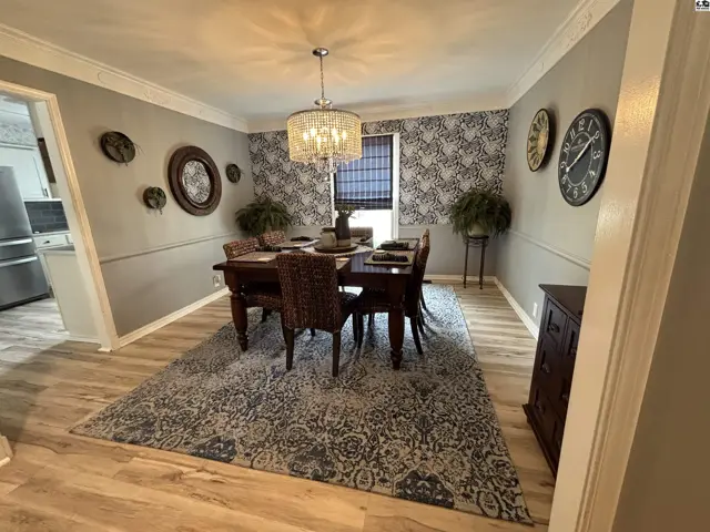 Elegant dining room with a dark wood table, wicker chairs, patterned wallpaper, and a crystal chandelier.