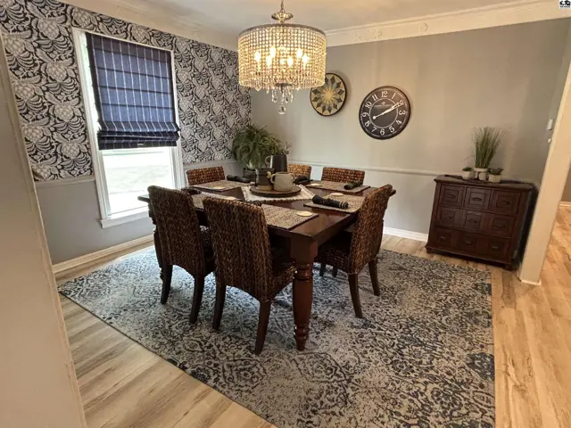 Elegant dining room with a patterned wallpaper, crystal chandelier, and dark wood furniture.