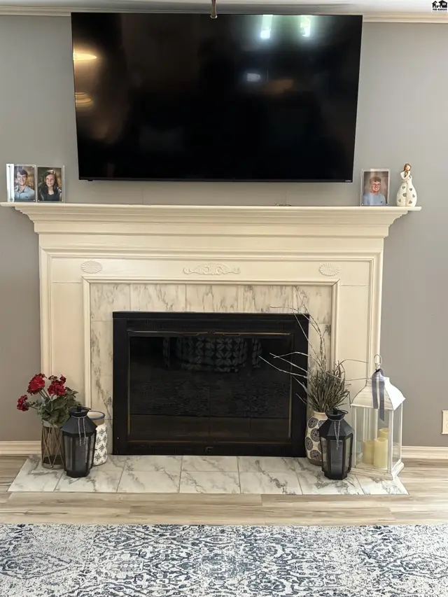 Elegant fireplace with marble surround, dark wood mantel, and mounted television.