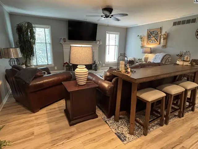 Spacious living room with leather furniture, a fireplace, and a large wooden dining table with stools.
