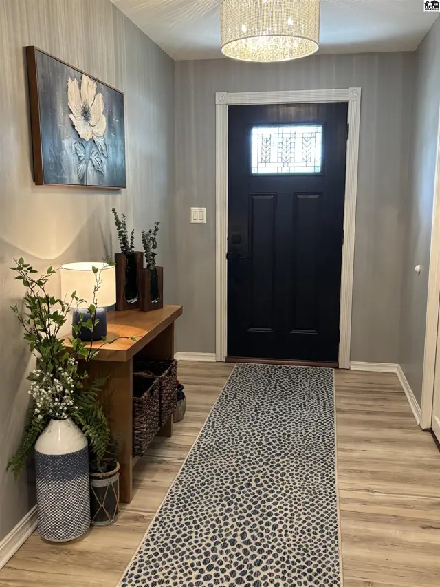 Entryway with black door, wood console table, patterned runner, and modern light fixture.