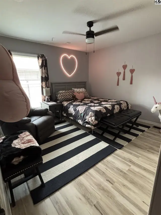Modern bedroom with a queen bed, black and white striped rug, and a neon heart accent.