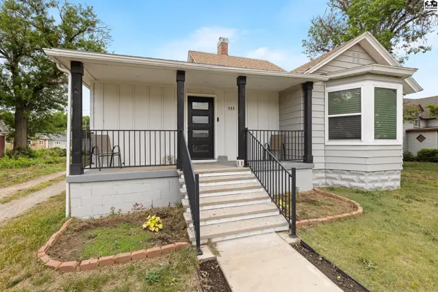 Charming bungalow with a covered porch, gray siding, white trim, and a bay window.