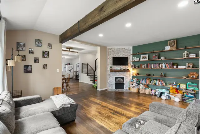 Spacious living room with a large sectional, brick fireplace, and a floor-to-ceiling bookshelf.