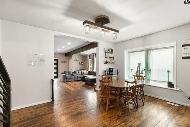 Dining area with wooden table and chairs opens to a living room with sectional sofa.